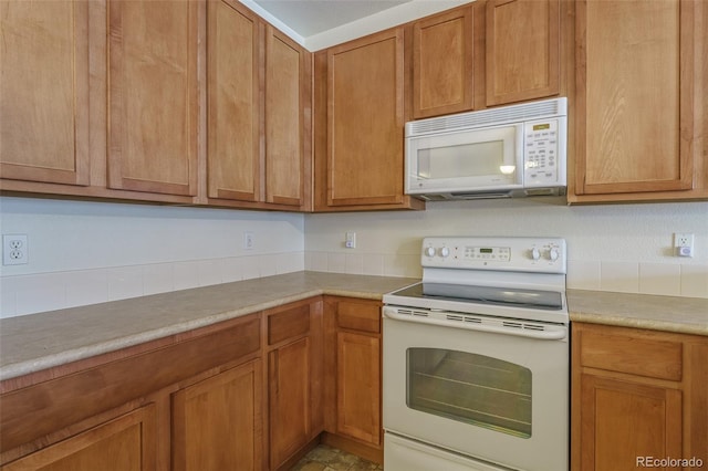 kitchen featuring light countertops, white appliances, and brown cabinets