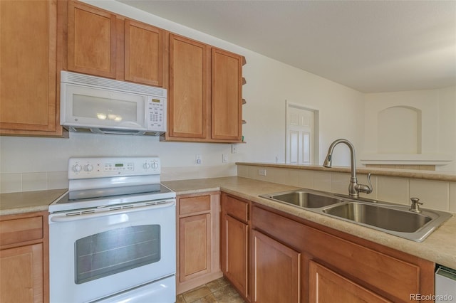 kitchen featuring brown cabinets, white appliances, light countertops, and a sink