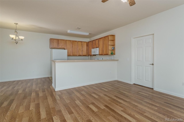 kitchen featuring decorative light fixtures, open shelves, wood finished floors, white appliances, and a peninsula