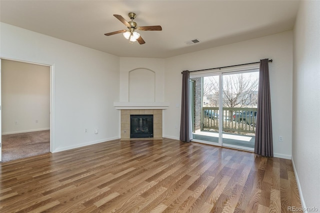 unfurnished living room featuring a fireplace, wood finished floors, visible vents, and baseboards