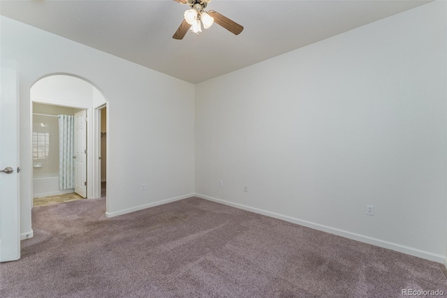 unfurnished room featuring arched walkways, light colored carpet, ceiling fan, and baseboards