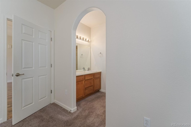 bathroom featuring double vanity, carpet, and baseboards