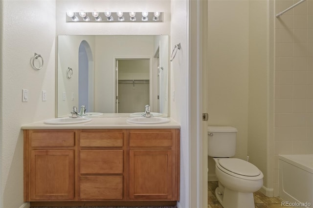 bathroom with double vanity, a closet, toilet, and a sink