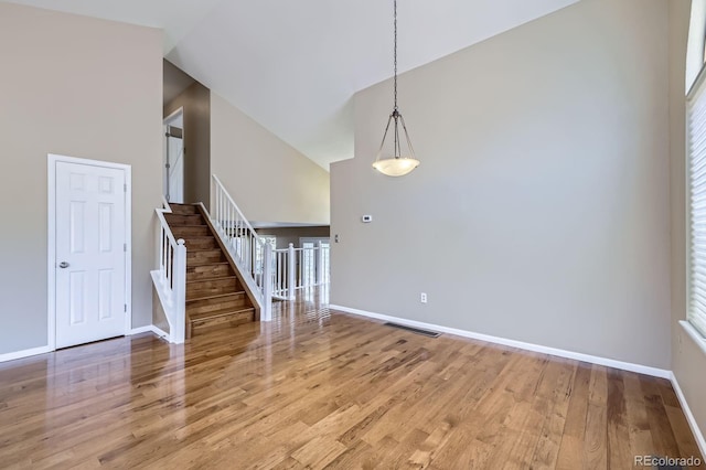 9916 Spring Hill Ln, Highlands Ranch, CO 80129 - spare room with wood finished floors, stairway, healthy amount of natural light, and high vaulted ceiling