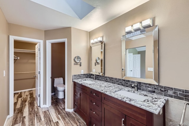 9916 Spring Hill Ln, Highlands Ranch, CO 80129 - full bathroom with wood finished floors, double vanity, a spacious closet, and decorative backsplash