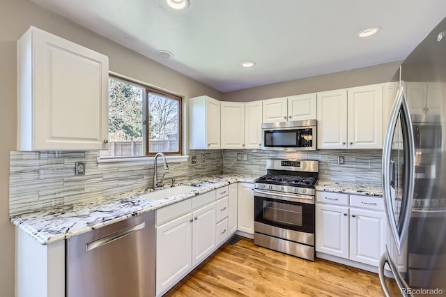 9916 Spring Hill Ln, Highlands Ranch, CO 80129 - kitchen with stainless steel appliances, light stone counters, white cabinetry, decorative backsplash, and recessed lighting