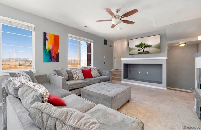 carpeted living room featuring baseboards, a fireplace, visible vents, and a ceiling fan