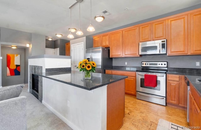 kitchen with a center island, stainless steel appliances, visible vents, hanging light fixtures, and dark stone countertops