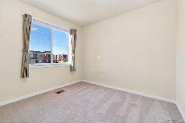 carpeted empty room featuring visible vents and baseboards