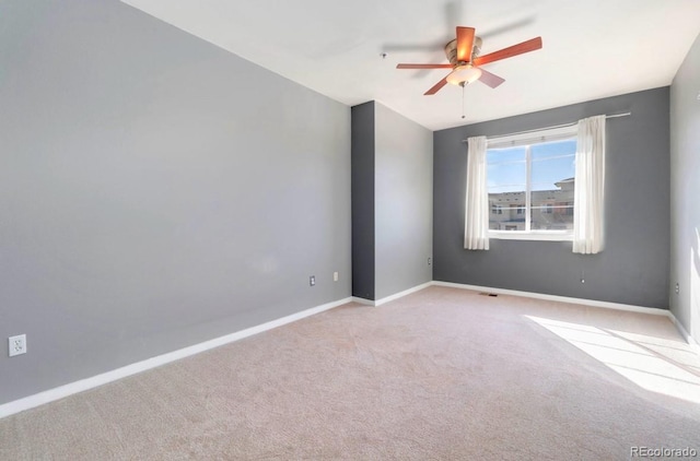 spare room featuring carpet floors, visible vents, ceiling fan, and baseboards