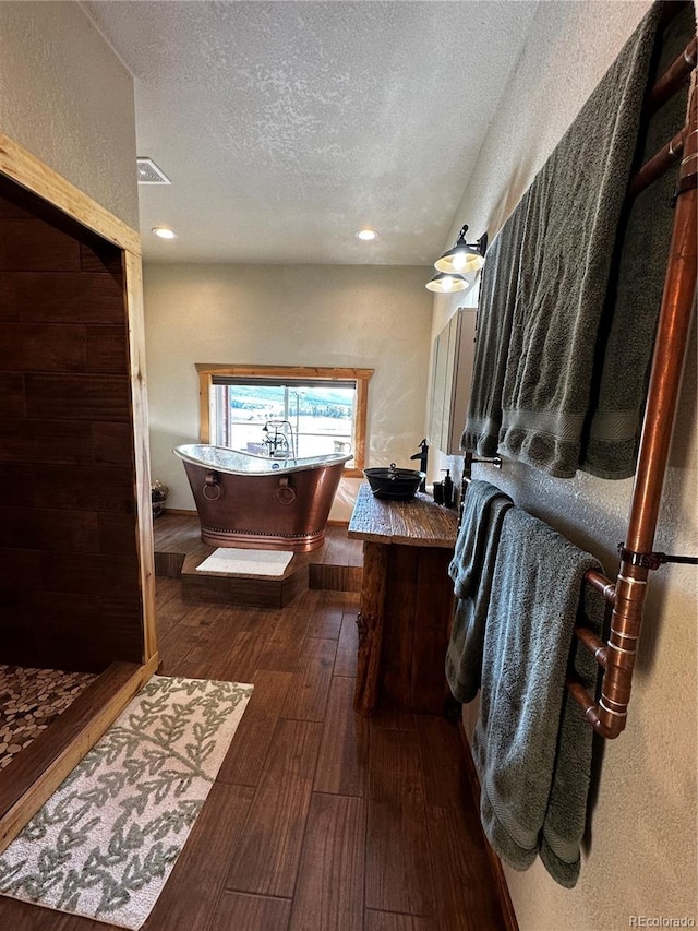 bathroom with wood-type flooring, vanity, a textured ceiling, and plus walk in shower