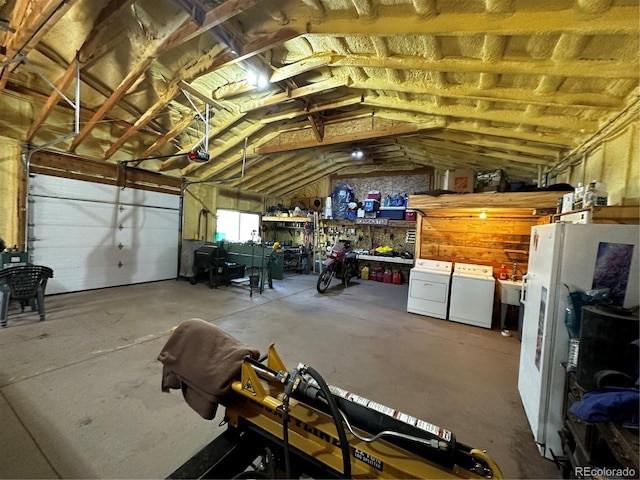 garage with white refrigerator, washing machine and dryer, and a workshop area