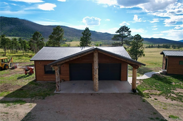 view of front facade featuring a mountain view, an outdoor structure, and a garage