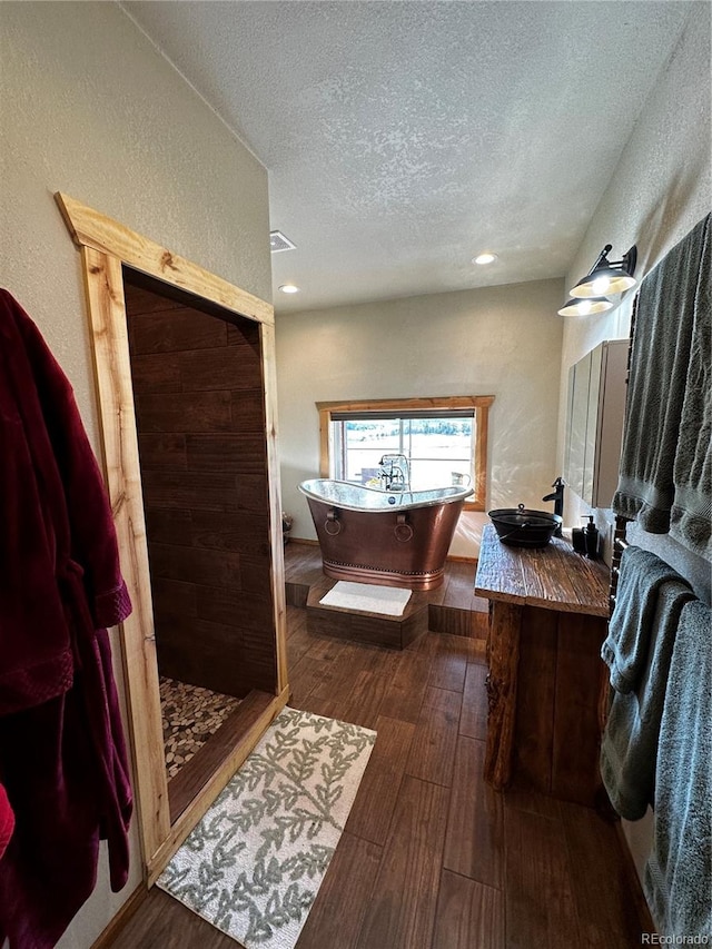 bathroom featuring a textured ceiling, independent shower and bath, vanity, and hardwood / wood-style flooring