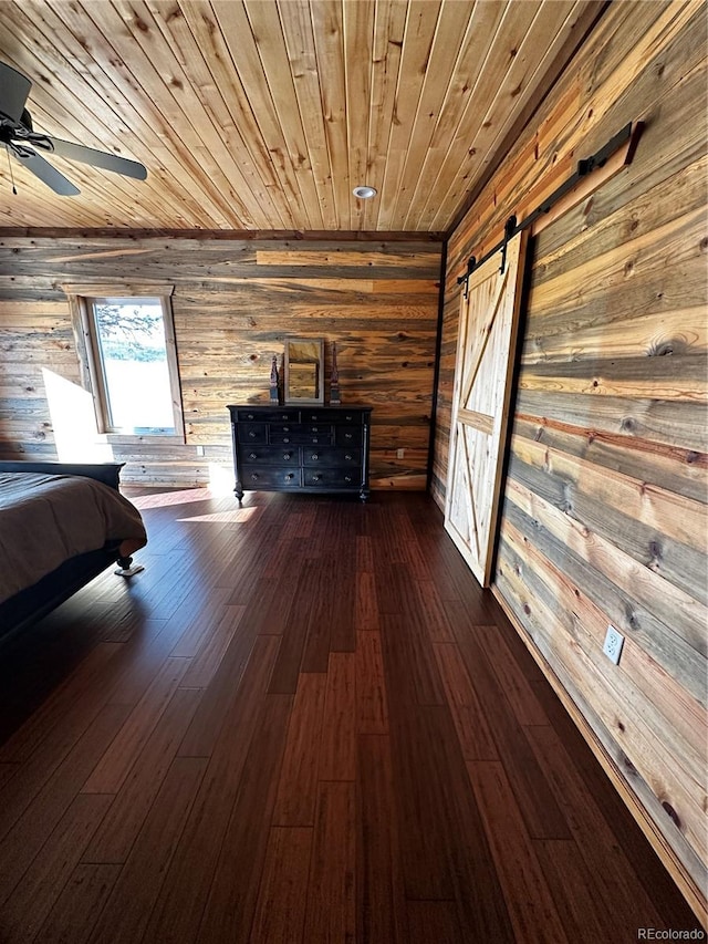 unfurnished bedroom with dark hardwood / wood-style flooring, wood walls, a barn door, and wooden ceiling