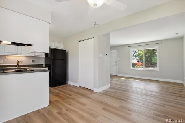 kitchen featuring black refrigerator, sink, white cabinets, ceiling fan, and light hardwood / wood-style flooring