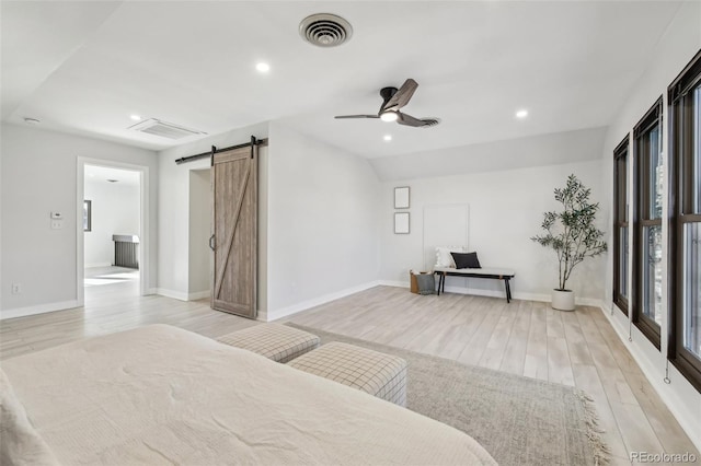 bedroom with light wood-type flooring, ceiling fan, lofted ceiling, and a barn door