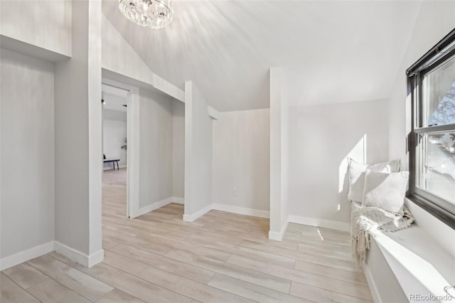 interior space featuring light wood-type flooring, a notable chandelier, and vaulted ceiling