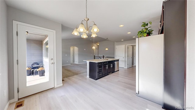 kitchen featuring light wood-style flooring, arched walkways, light countertops, and decorative light fixtures