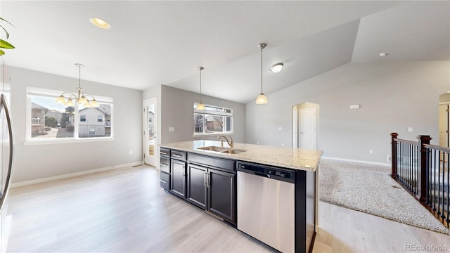 kitchen featuring pendant lighting, vaulted ceiling, a sink, light stone countertops, and dishwasher