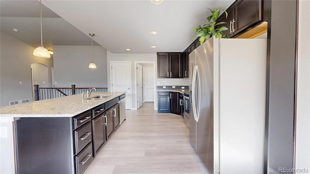 kitchen featuring stainless steel appliances, a sink, visible vents, light wood-style floors, and dark brown cabinets