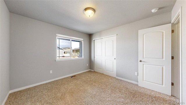 unfurnished bedroom with light carpet, a closet, visible vents, and baseboards