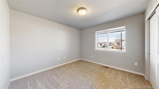 empty room featuring baseboards, visible vents, and carpet flooring