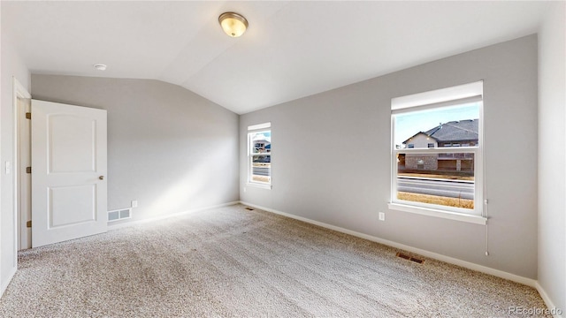 unfurnished room with vaulted ceiling, carpet flooring, visible vents, and baseboards