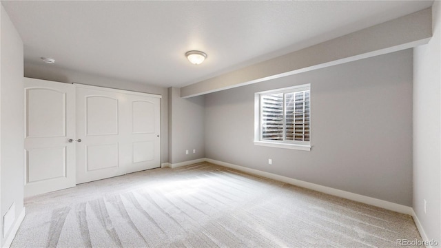 unfurnished bedroom featuring carpet floors, baseboards, and a closet