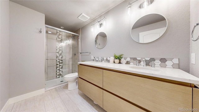 bathroom with a stall shower, a sink, toilet, and double vanity