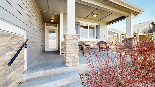 view of exterior entry with covered porch and stone siding