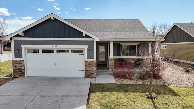 view of front of property with an attached garage, driveway, stone siding, board and batten siding, and a front yard