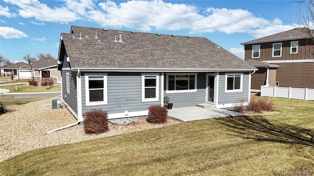 rear view of house featuring central AC unit, a shingled roof, fence, a yard, and a patio area