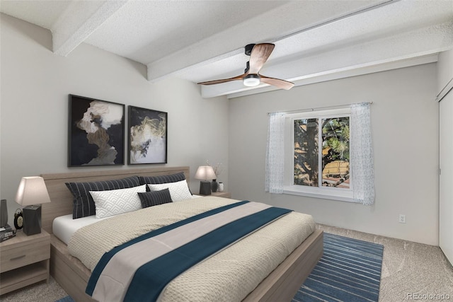 carpeted bedroom with ceiling fan, beamed ceiling, and a textured ceiling