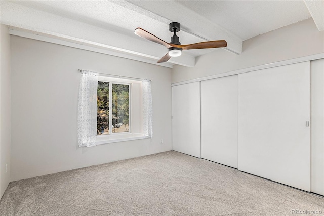 unfurnished bedroom featuring a textured ceiling, ceiling fan, light carpet, and a closet