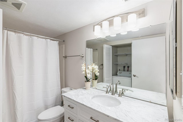 bathroom featuring washer / clothes dryer, vanity, a textured ceiling, walk in shower, and toilet