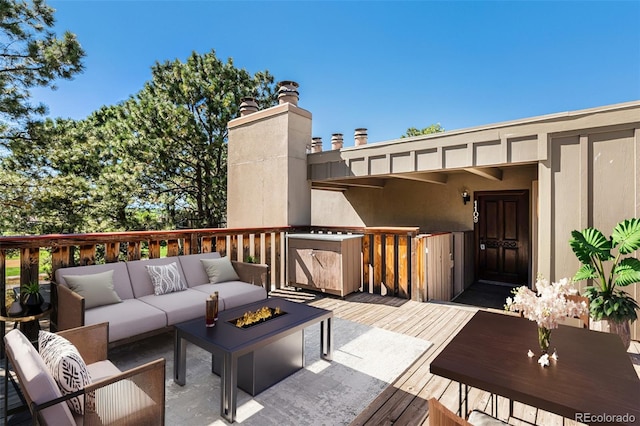 wooden terrace featuring an outdoor living space with a fire pit