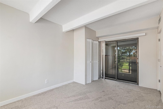 carpeted empty room with a textured ceiling and beam ceiling