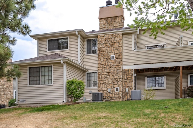 rear view of house with a lawn, central air condition unit, stone siding, and a chimney