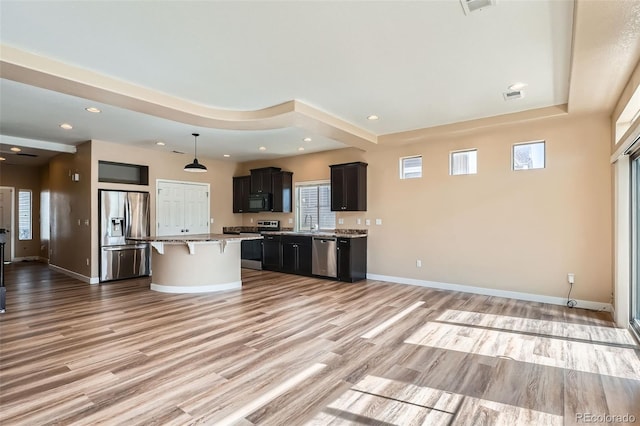 4625 Walden Ct, Denver, CO 80249 - kitchen with appliances with stainless steel finishes, a kitchen breakfast bar, light wood-type flooring, a center island, and recessed lighting