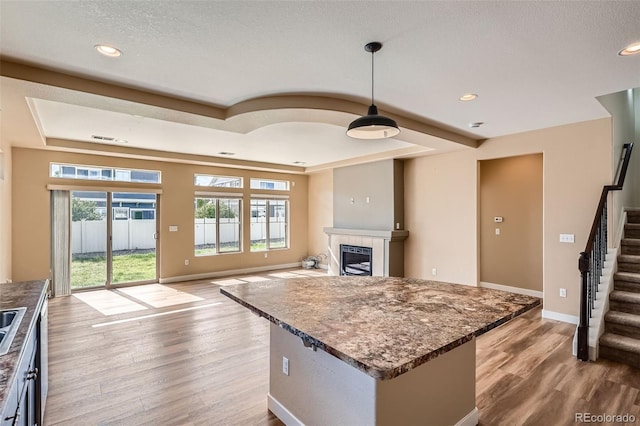 4625 Walden Ct, Denver, CO 80249 - kitchen with light wood-style floors, a tile fireplace, a raised ceiling, recessed lighting, and pendant lighting