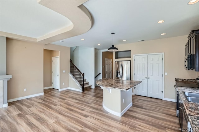 4625 Walden Ct, Denver, CO 80249 - kitchen with appliances with stainless steel finishes, a center island, light wood-style flooring, a breakfast bar, and recessed lighting