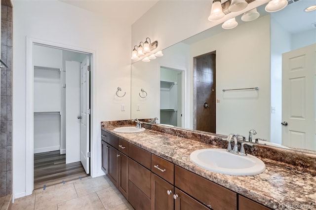 4625 Walden Ct, Denver, CO 80249 - bathroom featuring a walk in closet, tile patterned flooring, double vanity, and a tile shower