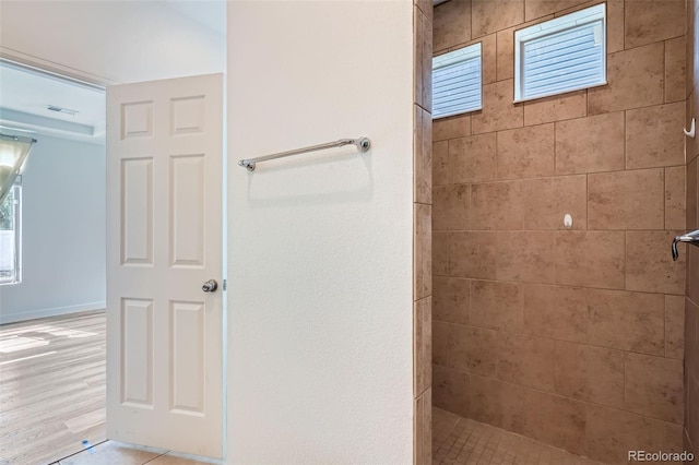 4625 Walden Ct, Denver, CO 80249 - full bathroom featuring a tile shower, healthy amount of natural light, and wood finished floors