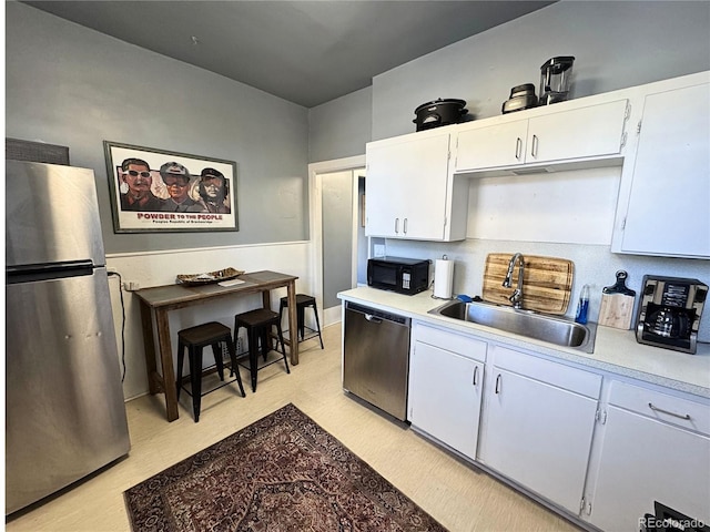 kitchen featuring light wood-type flooring, appliances with stainless steel finishes, sink, and white cabinets