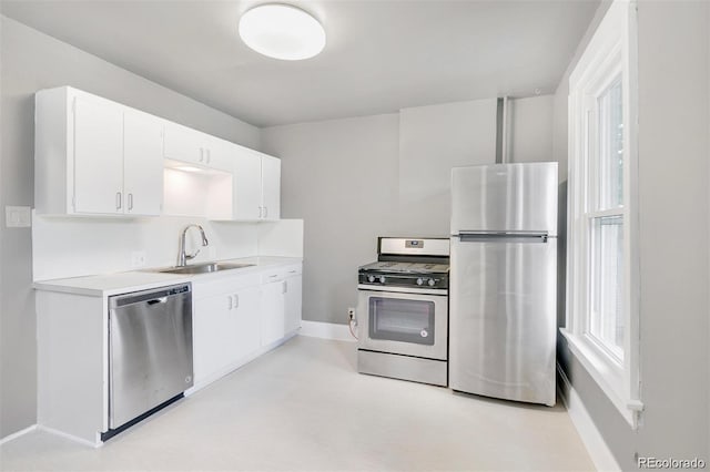 kitchen featuring stainless steel appliances, a wealth of natural light, sink, and white cabinets