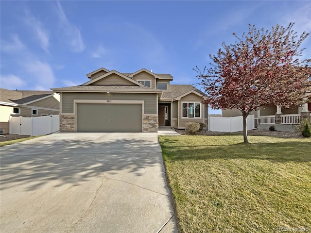 8612 13th St, Greeley, CO 80634 - view of front of home with a front lawn, driveway, stone siding, fence, and a garage