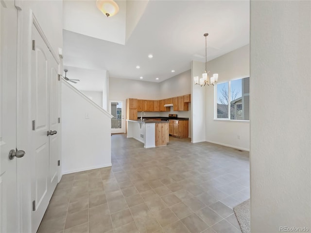 8612 13th St, Greeley, CO 80634 - kitchen with dark countertops, open floor plan, baseboards, a notable chandelier, and brown cabinetry