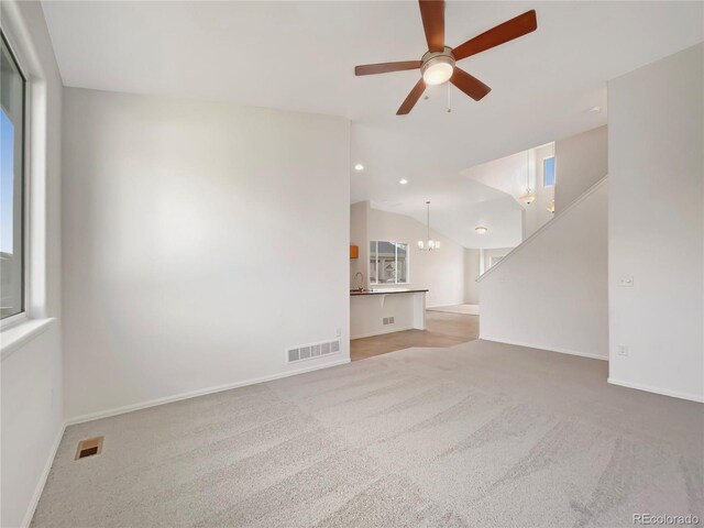 8612 13th St, Greeley, CO 80634 - unfurnished living room featuring light colored carpet, vaulted ceiling, visible vents, and ceiling fan with notable chandelier