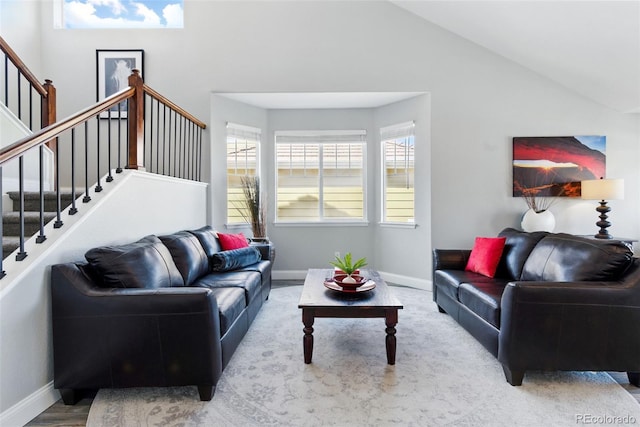 living room with baseboards, high vaulted ceiling, and stairs